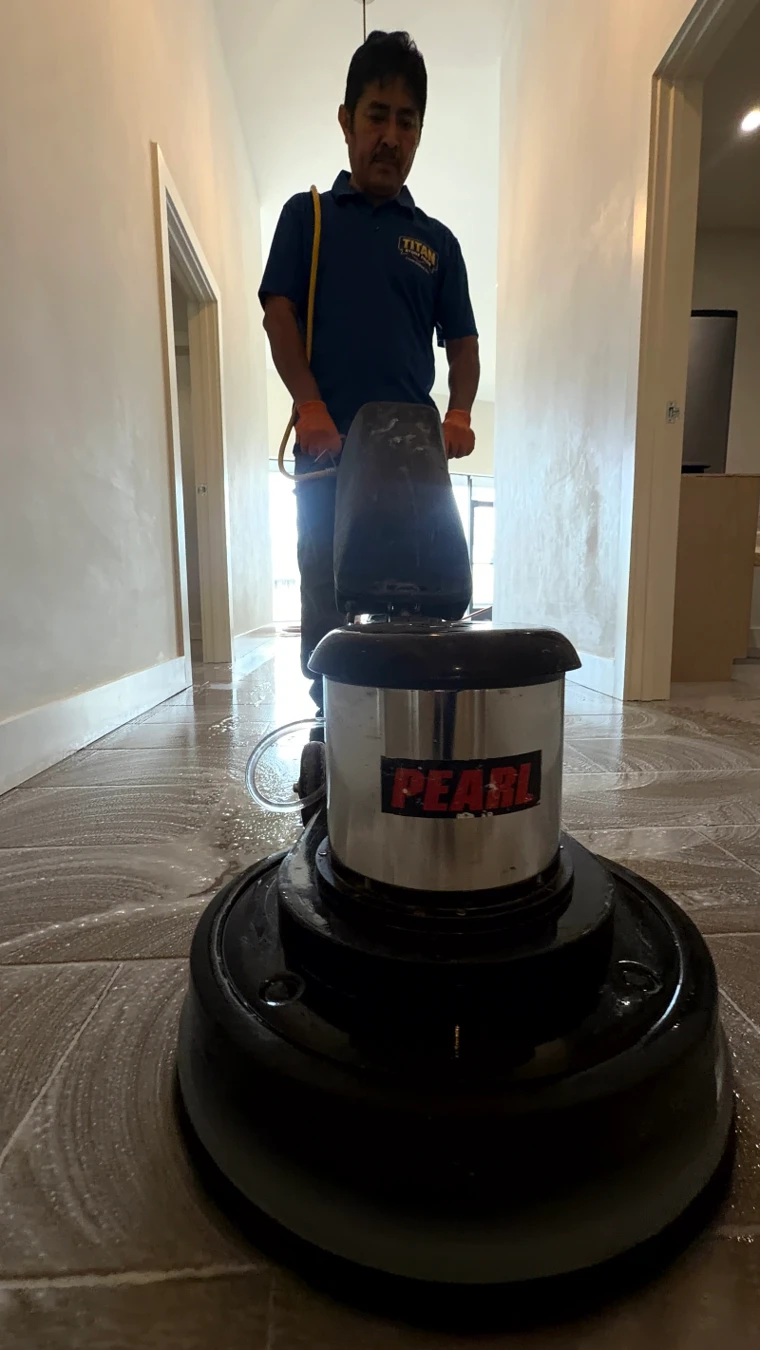 A Titan Stone Pros technician running a floor machine across a wet stone floor