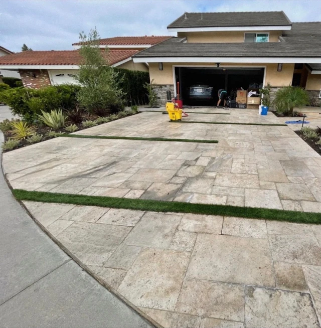 The same travertine driveway before cleaning, stained and streaked with the crew's equipment still on it