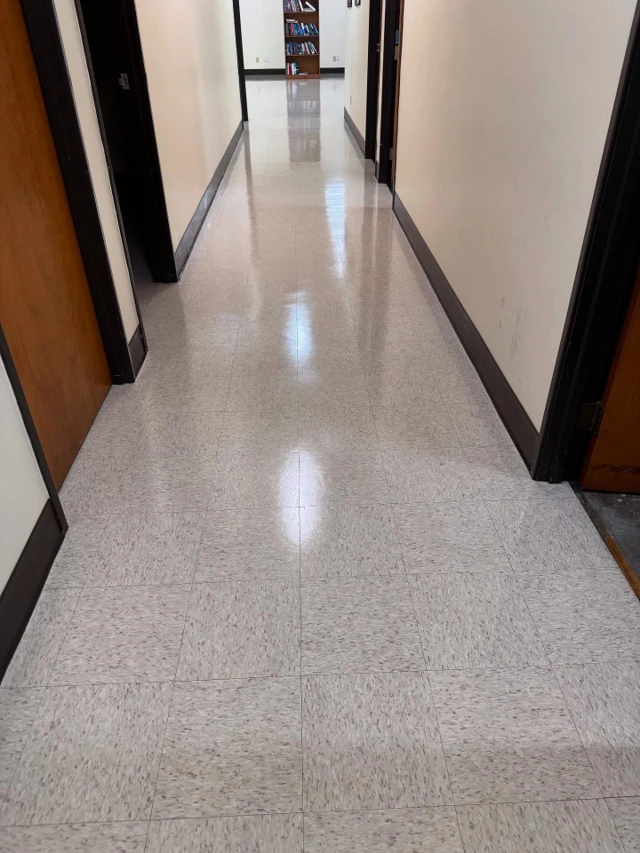 Office corridor VCT floor after stripping and waxing, reflecting the length of the hallway